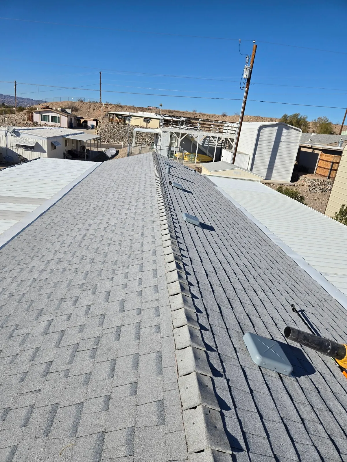 New gray architectural shingle roof with a finished ridge line under a clear Arizona sky